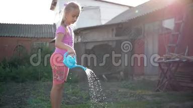 小女孩在花园里浇水。 可爱的小女孩园丁与浇水罐。